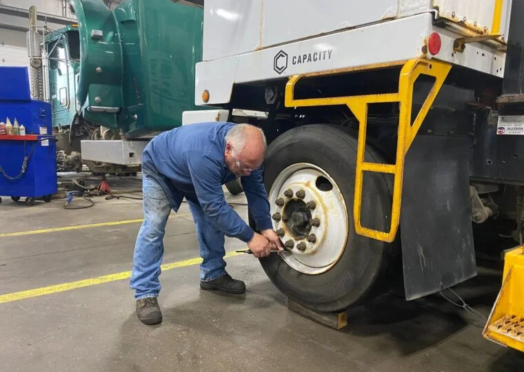 checking air pressure in semi truck tires for preventative maintenance - Blaine Bros.